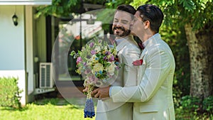 LGBTQ gay couple holding bouquet and hugging together in wedding ceremony