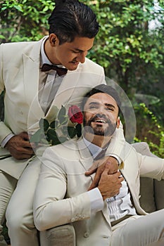 LGBTQ gay couple sitting together in living room in wedding ceremony