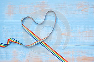 LGBTQ with heart shape Rainbow ribbon on blue pastel wooden background for Lesbian, Gay, Bisexual, Transgender and Queer community