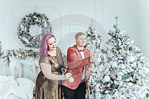LGBTQ lesbian couple celebrating Christmas or New Year winter holiday together. Gay female lady with butch partner decorating