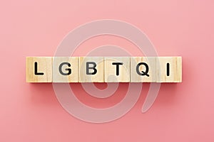 LGBTQI letters on wooden cubes over pink background. Abstract concept of human rights, diversity, equality