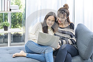 Lgbtqia Concept. Two women use laptop computer on the sofa in the living room
