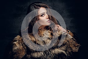 Brunette woman with long curly hair dressed in a fur coat. photo