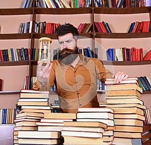 Librarian concept. Teacher, scientist with beard stands at table with books, defocused. Man on thoughtful face stands