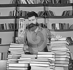 Librarian concept. Teacher, scientist with beard stands at table with books, defocused. Man on thoughtful face stands