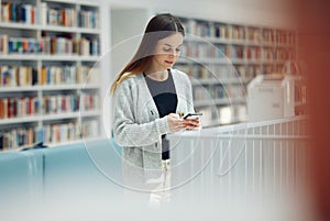 Library, phone and woman student networking on social media, mobile app or internet in college. Bookstore, knowledge and