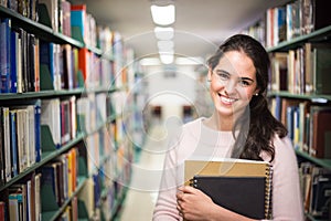 In the library - pretty female student with books working in a h