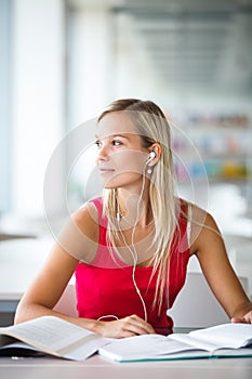 Pretty female student with books working in a high school library