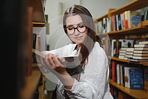 in the library - pretty female student with books working in a high school library.