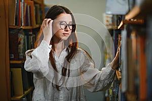 in the library - pretty female student with books working in a high school library.