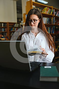 in the library - pretty female student with books working in a high school library.