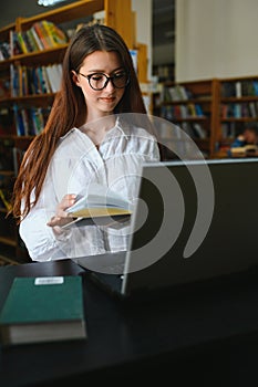 in the library - pretty female student with books working in a high school library.