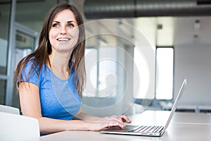 In the library - pretty female student with laptop and books