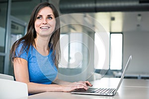 In the library - pretty female student with laptop and books