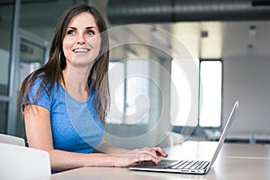 In the library - pretty female student with laptop and books