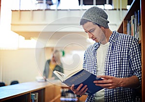 The librarys the best place to study. a university student reading a book in the library at campus. photo