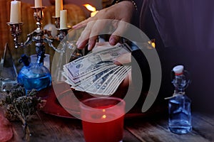 Librate with money, female hands of psychic doing witchcraft passes with dollars, esoteric Oracle performs ritual of removing photo