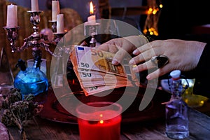Librate with money, female hands of psychic doing witchcraft passes with euro banknotes, esoteric Oracle performs ritual of photo