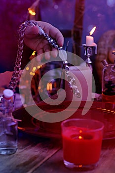 Librate with pendulum, healing or oracle foretelling, magic session, Female Fortuneteller or esoteric Oracle performs spell, photo