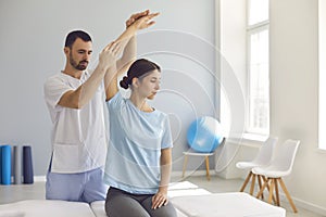 Licensed chiropractor or physiotherapist examining young woman`s arm in modern clinic