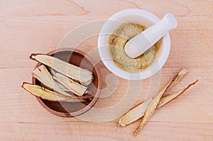 Licorice herbal medicine including powder, chopped and sliced root and mortar on wooden table