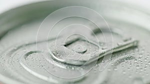 The lid of the aluminum can from the carbonated drink is covered with droplets of condensate.