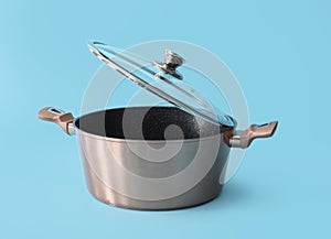 Lid and stainless cooking pot on color background