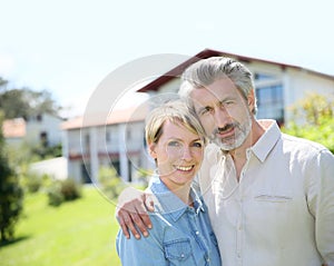 Liddle-aged couple standing on front of the house