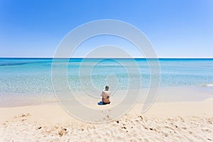 Lido Venere, Apulia - A young mother sitting on the beach looking towards the horizon