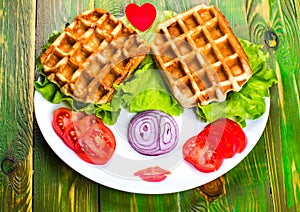 Liege waffles, tomato, onion and lettuce on a white plate.