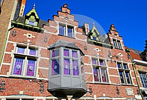 View on isolated red brick facade of medieval belgian house, gabled roof, bay window, clear blue sky