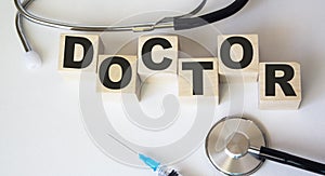 lies a stethoscope, a prick and wooden cubes with the text Doctor