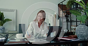 Life balance concept. Happy successful Caucasian business woman using laptop, taking notes and thinking at modern office