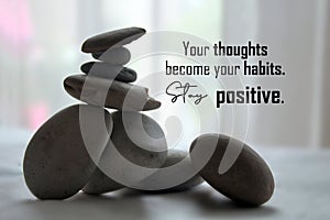 Life balance inspirational quote - Your thoughts become your habits. Stay positive. With zen stones on light white background.