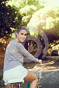 Life is a beautiful ride. Portrait of an attractive young woman riding her bicycle outside.