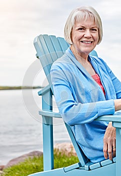 Life begins at retirement. Portrait of a happy senior woman relaxing on a chair outside.