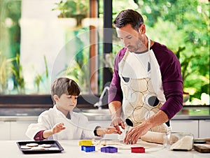 Life is better with fresh baked cookies. a father and son baking biscuits in the kitchen.