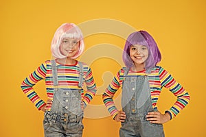 Life is better with friends. Happy girls friends on yellow background. Little friends smile in fashionable hair wigs and