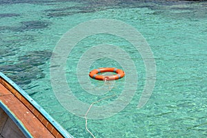 Life buoy floating on clear blue sea water near the tourist boat.