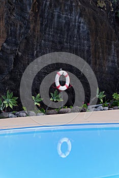 Life buoy hanging on dark rocky wall at pool
