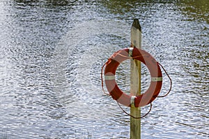 Life buoy hanging on a pole with water in the background