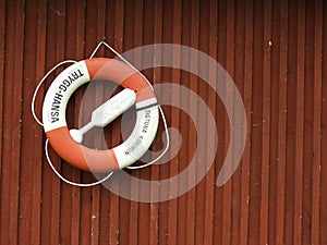 Life buoy hanging on a red wooden wall