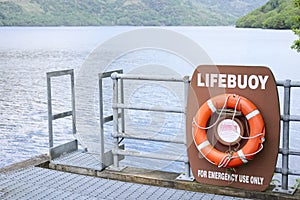 Life buoy orange red ring water safety prevention drowning scenic view inversnaid Loch Lomond Scotland uk