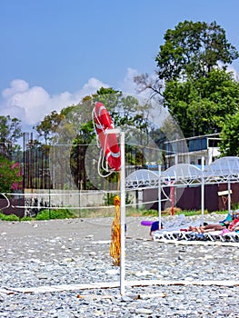 Life buoy on a pole on a beach with blue ocean water