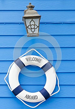 Life buoy welcome aboard sign and old lamp