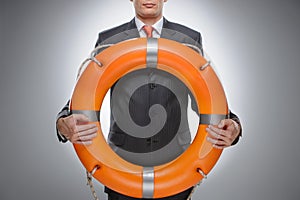 Life buoy for your business. Businessman holding a life belt while isolated on gray