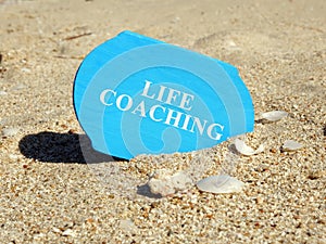 Life coaching sign on a plank in sand.