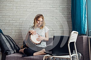 Life in coronavirus quarantine, education and activities at home during lockdown. Pretty young woman makes music playing the