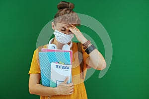 Stressed young student in yellow shirt isolated on green