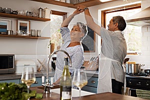 Life is delightful when youre dancing. a happy mature couple dancing together while cooking in the kitchen at home.